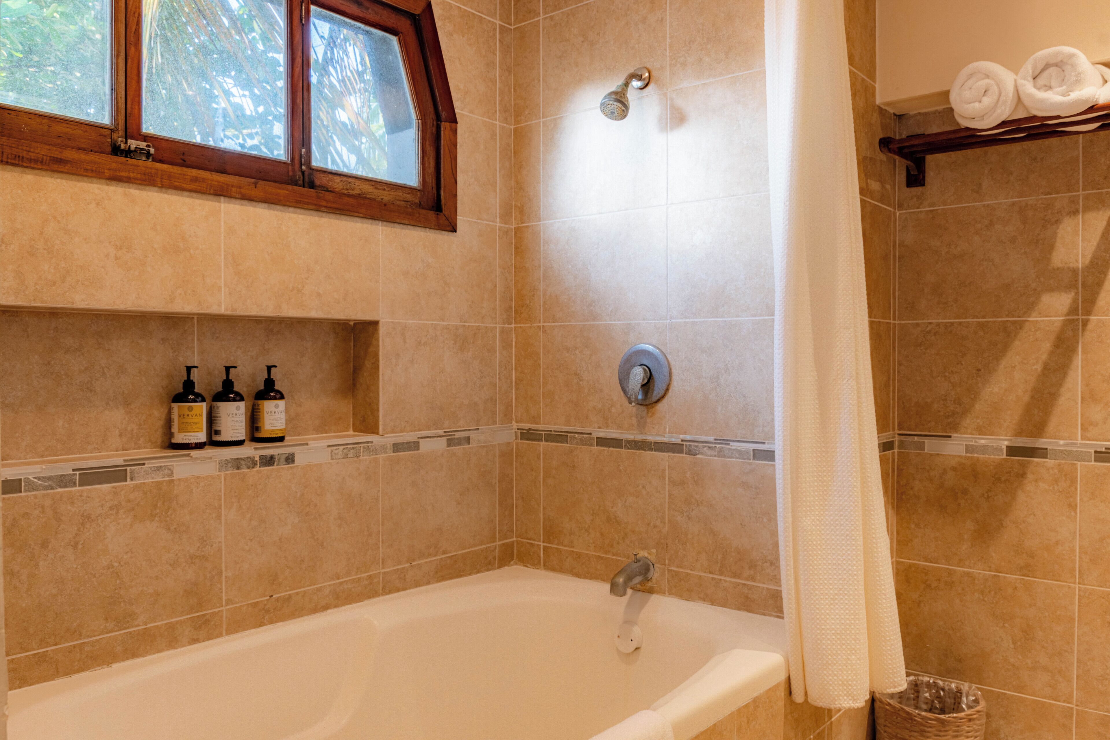 A bathroom with a bathtub, a showerhead, and a window.
