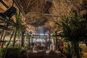 Un espacio interior con techo alto, luz natural y variados arreglos de asientos.