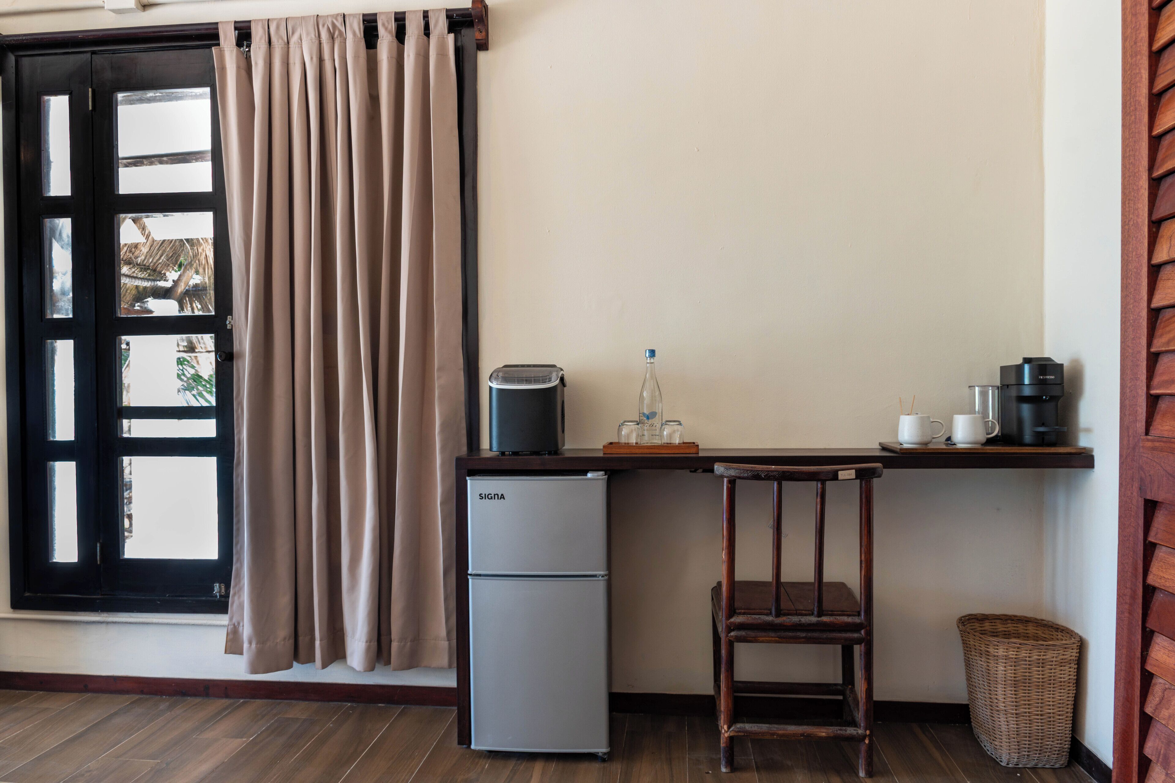 A compact kitchen with a refrigerator, a coffee maker, and a small table.
