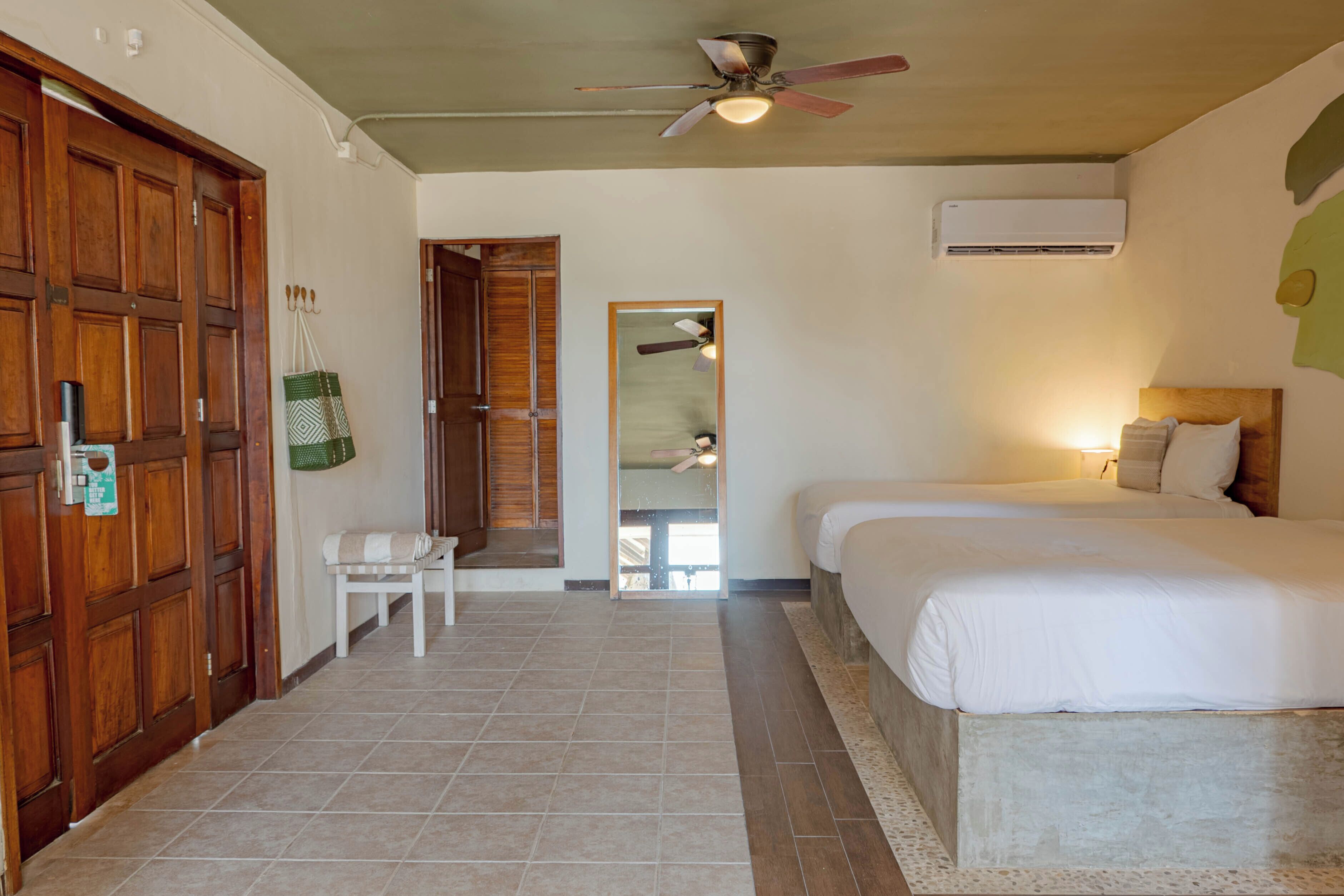 A hotel room with a bed, a chair, a wooden door, and a ceiling fan.