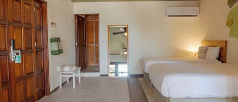 A hotel room with a bed, a chair, a wooden door, and a ceiling fan.