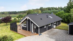 A single-story cabin with a dark exterior, a sloped roof, and a wooden deck. - Gorgeous home in Ebeltoft with sauna (Ebeltoft)