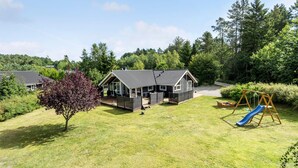 A house with a large deck, surrounded by a grassy yard and trees. - Gorgeous home in Ebeltoft with sauna (Ebeltoft)