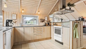 A modern kitchen with wooden cabinets, a built-in oven, and a window overlooking a garden. - Gorgeous home in Ebeltoft with sauna (Ebeltoft)