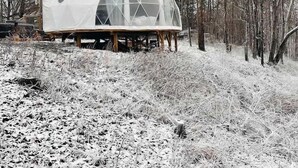 Una struttura a cupola geodetica su palafitte in una foresta innevata.