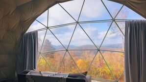 Una tenda con un design geometrico per la finestra, un letto e vista sui colori dell'autunno.