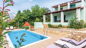 Une piscine avec des chaises longues, un patio couvert et un mur en pierre.