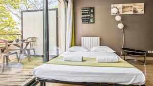 Un dormitorio moderno con una cama grande, una mesita de noche, una silla y vistas al exterior.