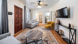 A modern living room with a sofa, armchair, coffee table, TV, and ceiling fan. - Jacuzzi Delight - Luxe 2BD/2BA near UC Davis Med (Sacramento)