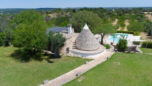 A stone structure with a conical roof, surrounded by a swimming pool and a well-maintained lawn. - 3 bedroom cozy home in Ostuni (Ostuni)
