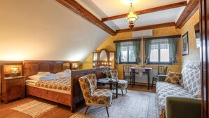 Une chambre mansardée chaleureuse avec un lit en bois, une table à manger avec des chaises et un lustre.