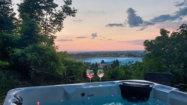 Un bain à remous avec vue sur un lac et des montagnes, au coucher du soleil.
