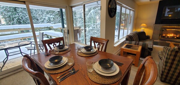 Enjoy meals together in this inviting dining area with a table for four, a comfortable couch, and a fireplace.