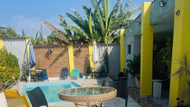 A poolside area with a round table, chairs, and two swan-shaped lounge chairs. - Pousada Cantinho de Piri (Pirenópolis)