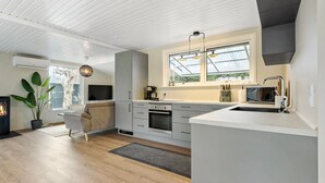 A modern kitchen with a large window, built-in appliances, and a cozy seating area. - 4 bedroom stunning home in Væggerløse (Væggerløse)