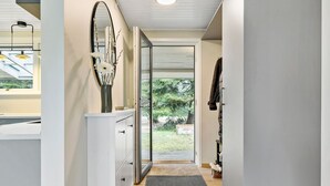 A hallway with a white cabinet, a mirror, and a door leading to an outdoor area with a view of trees. - 4 bedroom stunning home in Væggerløse (Væggerløse)