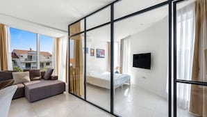 Moderni hotellihuone, jossa on suuri liukuovi, sänky, televisio ja sohva.