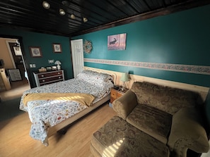 Une chambre à coucher avec un lit, un canapé, une commode et un mur orné d’un tableau.