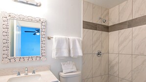 Ein Badezimmer mit Marmorwaschbecken, Toilette und Dusche mit einer Wandverkleidung aus Holz.