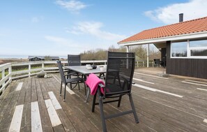Une terrasse extérieure avec une table et des chaises, une vue sur la mer et un bâtiment avec un toit recouvert de tuiles rouges.