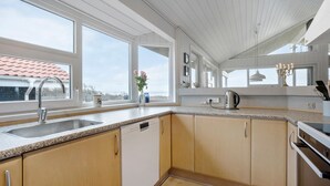 Una cocina moderna con un ventanal grande, lavavajillas integrado y estufa.