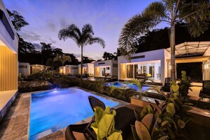 A pool area with multiple pools, lounge chairs, and palm trees. - Villas Ríos del Caribe (Cahuita)