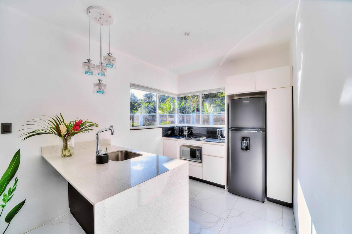 Cozinha moderna com ilha central, eletrodomésticos de aço inoxidável e vista para o verde lá fora.