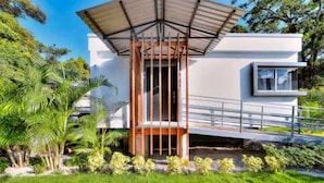 Un bâtiment moderne à la façade blanche, doté d’un porche et d’une petite fenêtre.