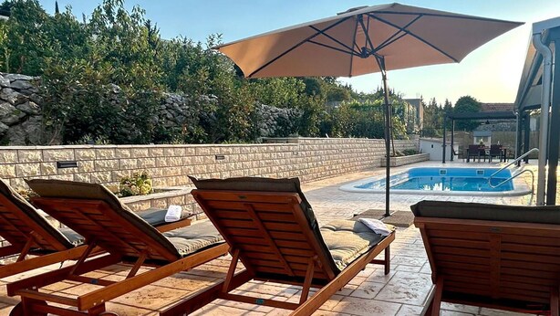 Un espace aménagé au bord de la piscine, avec des chaises longues et un grand parasol.