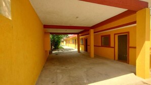 Un couloir aux murs jaunes et aux touches de couleur rouge, qui mène à un bâtiment doté de nombreuses portes.