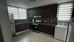 Eine moderne Küche mit dunklen Schränken, einem Edelstahlherd, einem Einbauofen, einem Geschirrspüler und einem Kühlschrank.
