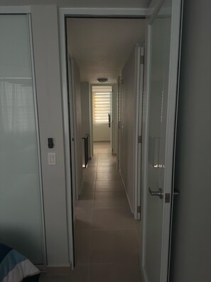 A corridor with a door on the left, a door on the right, and a window with blinds at the end. - Spacious Family Friendly 4BR Home Near Beach (Mansión del Mar)