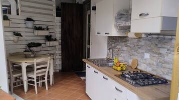A compact kitchen with white cabinets, a wooden countertop, and a tiled floor.