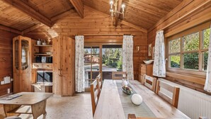 A wooden cabin interior with a dining table, chairs, a chandelier, and large windows. - Pet friendly home in Haren with WiFi (Haren)