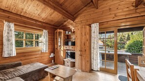 A cozy cabin interior with a wooden interior, a sofa, a table, and a sliding glass door leading to an outdoor area. - Pet friendly home in Haren with WiFi (Haren)