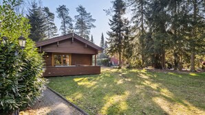 A wooden cabin with a porch, surrounded by a grassy yard and tall trees. - Pet friendly home in Haren with WiFi (Haren)