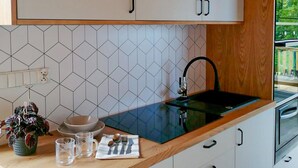 Une cuisine moderne avec des meubles blancs, un plan de travail noir et un dosseret de carrelage à motifs géométriques.