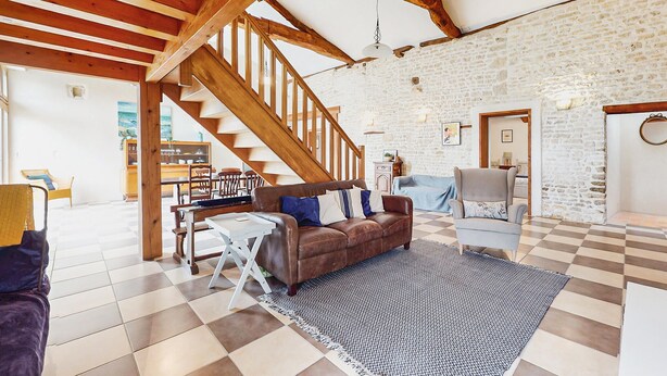 A spacious living area with a wooden staircase, a checkered floor, and a stone wall. - Pet friendly home in NERE (NERE)