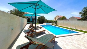Una piscina amb gandules i un parasol gran.