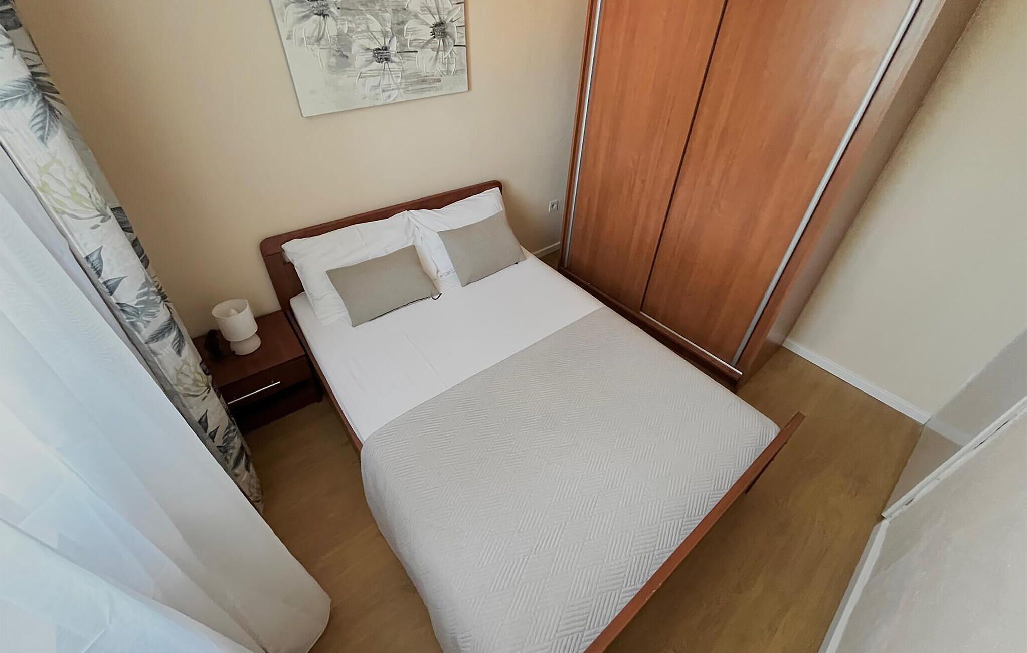 Ein ordentlich eingerichtetes Schlafzimmer mit einem Bett, einem Nachttisch und einem Holzschrank.