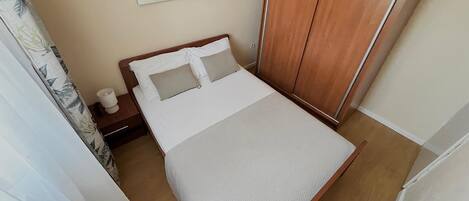 Ein ordentlich eingerichtetes Schlafzimmer mit einem Bett, einem Nachttisch und einem Holzschrank.