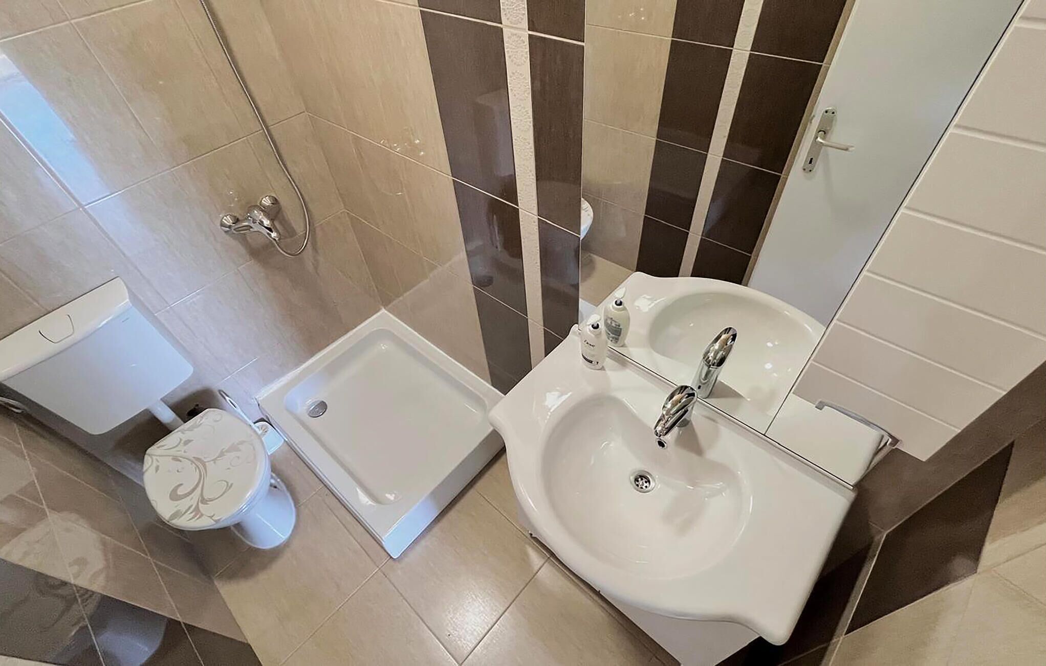 A bathroom with a toilet, shower, and sink.