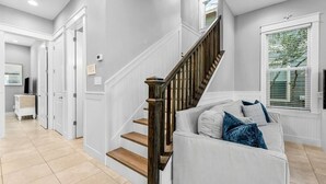 Un pasillo amplio con una escalera que conduce a una sala de estar.
