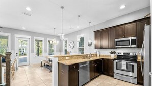 Una cocina moderna con armarios oscuros, electrodomésticos de acero inoxidable y una isla grande.