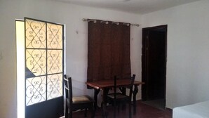 Una habitación con escritorio de madera, dos sillas, una cortina y una ventana con paneles de vidrio decorativos.