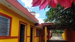 Un edificio amarillo con detalles rojos y un camino de hormigón.