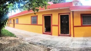 Un edificio amarillo con un espacio al aire libre cubierto, varias puertas y ventanas.