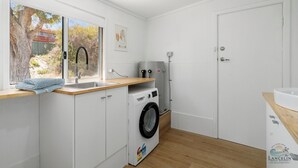 A compact laundry room with a washing machine, a dryer, and a water heater. - Playgrounds -Your perfect Family Getaway Awaits! (Lancelin)