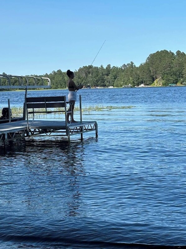 Um cais com um banco e alguém pescando.