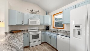 A kitchen with light blue cabinets, a white refrigerator, a microwave, an oven, and a sink. - Coastal Retreat with Beautiful views-completely updated for a cozy stay! (Kitty Hawk)